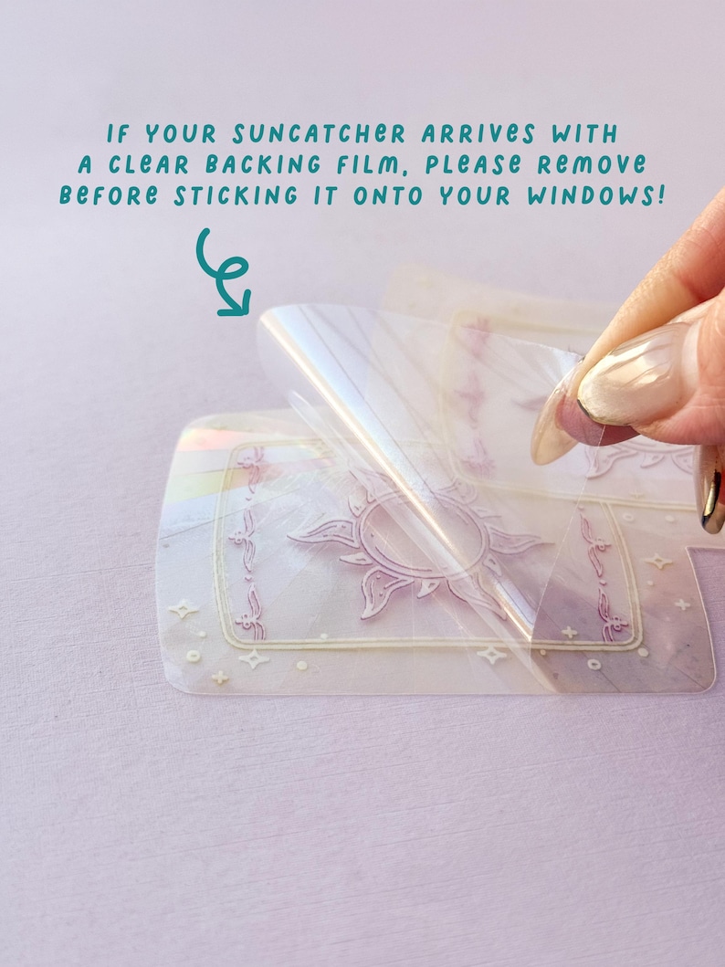 May include: A clear protective film is being peeled off a suncatcher with a sun and stars design. The text "IF YOUR SUNCATCHER ARRIVES WITH A CLEAR BACKING FILM, PLEASE REMOVE BEFORE STICKING IT ONTO YOUR WINDOWS!" is visible in the image.