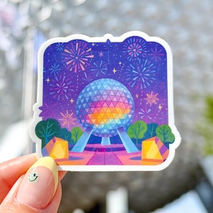 May include: A sticker featuring a colorful illustration of the Spaceship Earth attraction at Epcot, with fireworks in the background. The attraction is a geodesic sphere with a rainbow color scheme.