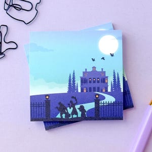 May include: A square sticky note featuring a graphic illustration of a dark mansion at night under a full moon. The scene includes silhouettes of three figures standing before a gated entrance, tall trees, and a winding path leading to the house.