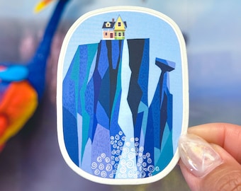 May include: A sticker featuring a cartoon illustration of a yellow house perched on a cliff with a waterfall cascading down the side. The house has a red roof and white trim. The cliff is a blue and purple color with white swirls at the bottom.