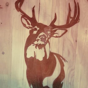 Peut inclure: Une silhouette de tête de cerf en métal rouillé avec de grands bois, montée sur un mur en bois.