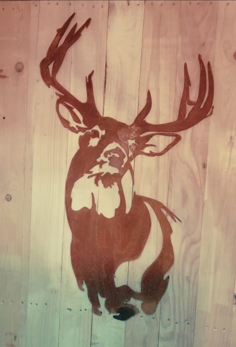 May include: A rusty metal silhouette of a deer head with large antlers mounted on a wooden wall.