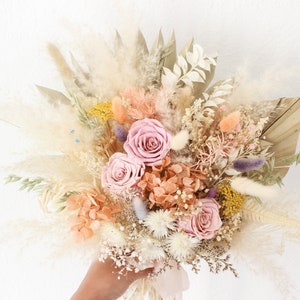 May include: A dried flower bouquet with pink roses, peachy-colored hydrangeas, and dried grasses in a boho style.