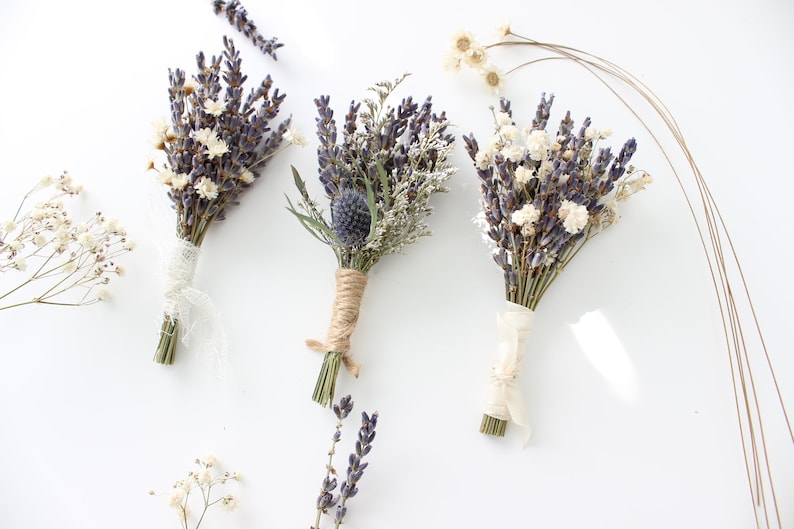 May include: Three small bouquets of dried lavender, white baby's breath, and other dried flowers tied with twine and ribbon.