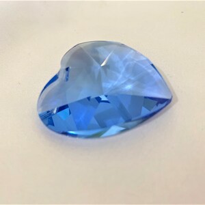May include: A light blue crystal heart charm with a faceted design. The heart is a popular shape for jewelry and crafts.