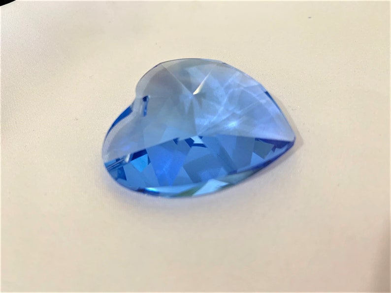 May include: A light blue crystal heart charm with a faceted design. The heart is a popular shape for jewelry and crafts.