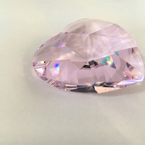 May include: A pink crystal heart shaped prism with iridescent facets.
