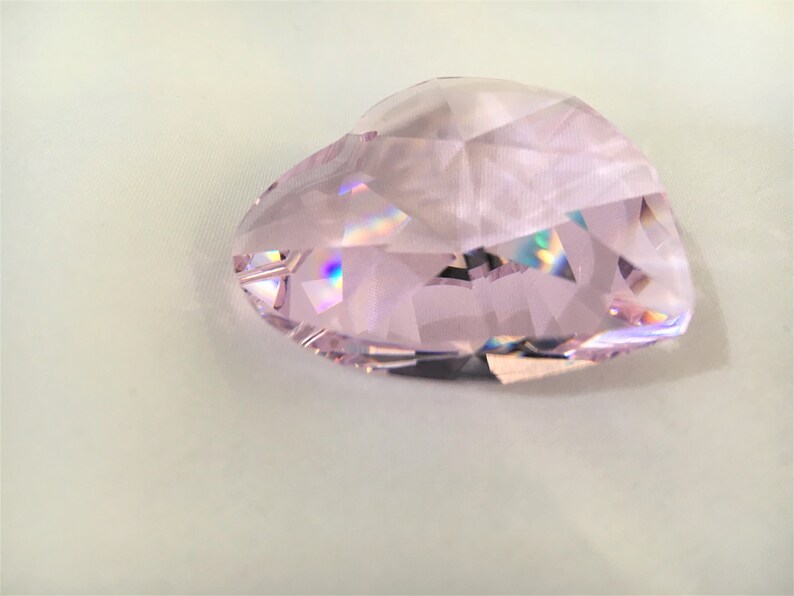 May include: A pink crystal heart shaped prism with iridescent facets.