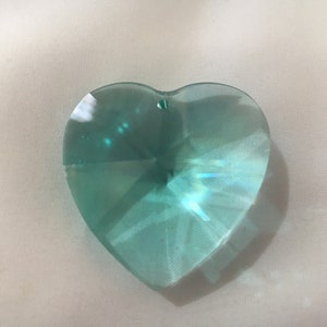 May include: A light blue heart-shaped crystal prism with a faceted design.