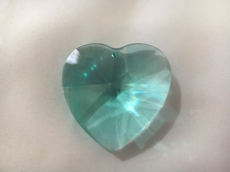 May include: A light blue heart-shaped crystal prism with a faceted design.
