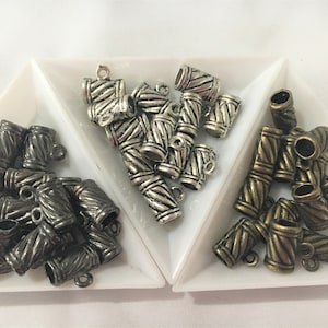 May include: Three piles of silver and bronze metal end caps for jewellery making. The end caps have a rope-like design.