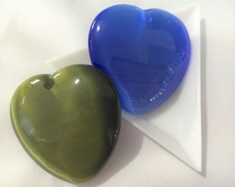 May include: Two heart-shaped polished stones, one blue and one green, on a white triangular surface.