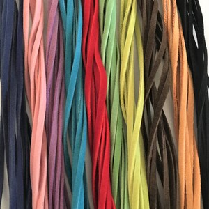 May include: Assortment of 14 different coloured suede leather cords. The cords are arranged in a row, with the colours ranging from dark blue to light orange.