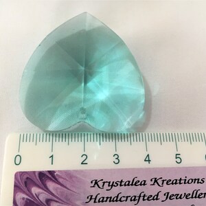 May include: A light blue heart-shaped crystal prism measuring approximately 2 inches in length. The prism is faceted and has a clear, glassy appearance.