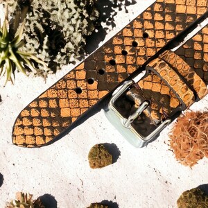 May include: A brown leather watch strap with a snakeskin pattern and a silver buckle.