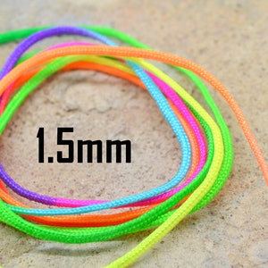 Puede incluir: Primer plano de un carrete de cordón de colores de 1,5 mm. El cordón está hecho de una variedad de colores brillantes, incluyendo verde, naranja, rosa, azul y morado.