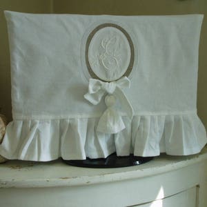 Shabby TV cover with ruffle in white linen and cotton, double medallion monogram and pompom.