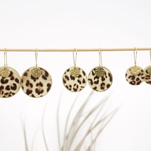 Peut inclure: Trois paires de boucles d'oreilles créoles dorées avec un motif léopard. Les boucles d'oreilles sont de tailles différentes.