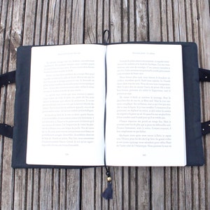 May include: A black book cover with a white bookmark and a tassel. The cover has a white polka dot pattern and two black handles.
