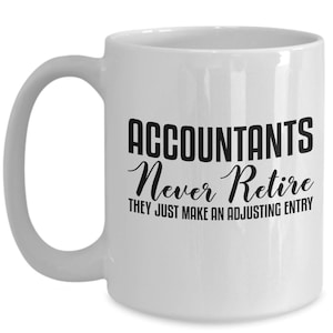 Op de afbeelding: Witte keramische koffiemok met een zwart ontwerp met de tekst "Accountants Never Retire They Just Make An Adjusting Entry".