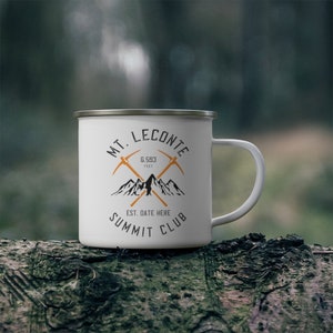 May include: White enamel camping mug with a black and orange logo that says "Mt. LeConte Summit Club" and "Est. Date Here" with a graphic of two crossed pickaxes and mountains. The logo also says "6,593 feet".