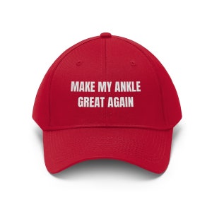 May include: Red baseball cap with white text that reads "Make My Ankle Great Again".