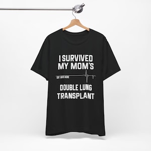 May include: Black t-shirt with white text that reads "I survived my mom's double lung transplant" with a heart rate line and the words "Est. Date Here" above the line.