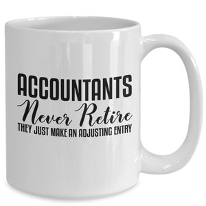 May include: White ceramic coffee mug with black text that reads "Accountants Never Retire They Just Make An Adjusting Entry".