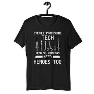 May include: Black t-shirt with white text that reads "Sterile Processing Tech Because Surgeons Need Heroes Too". The text is surrounded by a graphic of surgical tools.