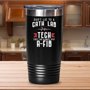 May include: Black stainless steel tumbler with a white graphic that reads "Don't lie to a Cath Lab Tech they can always spot A-Fib".