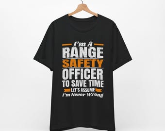 Puede incluir: Camiseta negra con texto blanco que dice "I'm a Range Safety Officer to save time let's assume I'm never wrong". El texto está en una fuente desgastada y tiene acentos naranjas.