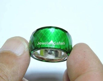 May include: A green ring with a faceted design. The ring is made of glass and has a silver band.