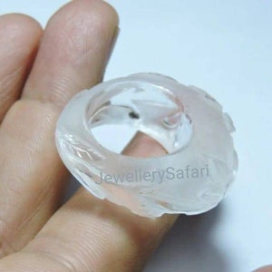 K&ouml;nnte beinhalten: Ein wei&szlig;er, durchsichtiger Ring mit einem geschnitzten Design. Der Ring ist aus einem Material, das wie Glas oder Plastik aussieht.