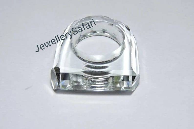 Puede incluir: Un porta anillos de cristal transparente con un dise&ntilde;o facetado. El porta anillos tiene forma de anillo y una base cuadrada.