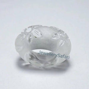 K&ouml;nnte beinhalten: Ein wei&szlig;er Ring mit einem floralen Design. Der Ring ist aus einem durchsichtigen Material gefertigt und hat eine glatte Oberfl&auml;che.