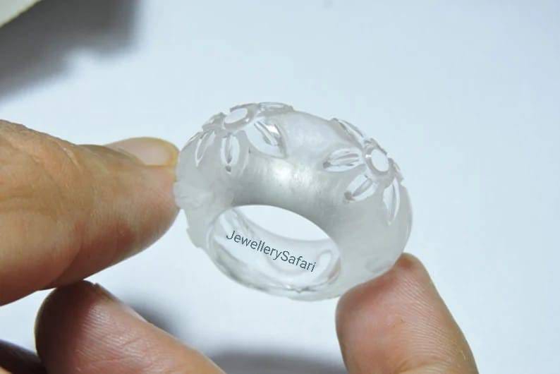 K&ouml;nnte beinhalten: Ein klarer, wei&szlig;er Ring mit einem floralen Design. Der Ring ist aus Wachs und wird von einer Hand gehalten. Der Text "JewellerySafari" ist auf dem Ring sichtbar.