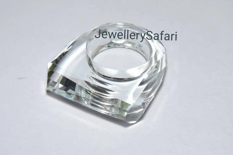Puede incluir: Un porta anillos de cristal transparente con una base cuadrada y una parte superior redondeada. El porta anillos est&aacute; dise&ntilde;ado para sujetar un anillo de forma segura.