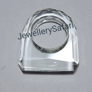 Puede incluir: Un porta anillos de cristal transparente con un dise&ntilde;o facetado. El porta anillos tiene forma de anillo y tiene una gran abertura en el centro.