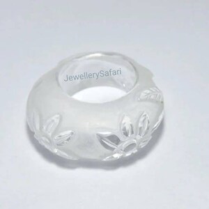 K&ouml;nnte beinhalten: Wei&szlig;er, gefrosteter Glasring mit Blumenmuster. Der Ring hat einen Durchmesser von etwa 2,5 cm.
