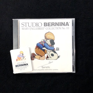 May include: A white CD case with a colorful illustration of a boy hugging a dog. The text on the case reads "Studio Bernina Mary Englebreit Collection No. 111".