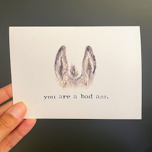 Eres una tarjeta de felicitación de cumplido mala en letra de máquina de escribir con sobre, ilustración de orejas y cola de burro, tarjeta divertida, aliento