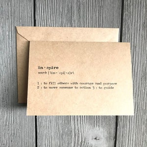 May include: A brown card with the word "inspire" defined as a verb. The definition is "to fill others with courage and purpose, to move someone to action, to guide."