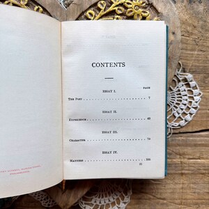 May include: A book with a teal green cover and the word "CONTENTS" printed in black. The book lists the essays "The Poet", "Experience", "Character", and "Manners" with their corresponding page numbers.