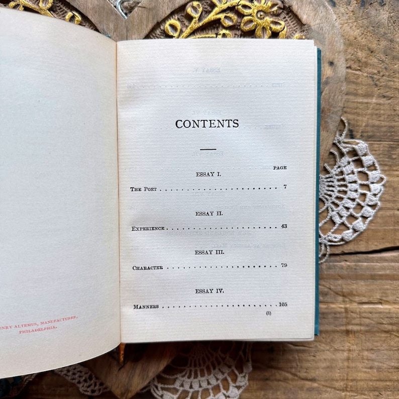 May include: A book with a teal green cover and the word "CONTENTS" printed in black. The book lists the essays "The Poet", "Experience", "Character", and "Manners" with their corresponding page numbers.