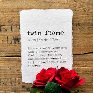 May include: A white paper print with the definition of "twin flame" in black text. The definition reads: "a mirror to your own soul. someone you feel a deep, familiar, and magnetic connection to. changes your life forever."