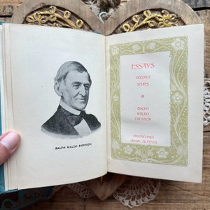 May include: A vintage book titled "Essays, Second Series" by Ralph Waldo Emerson. The book cover features a portrait of Emerson and a decorative border with floral motifs.