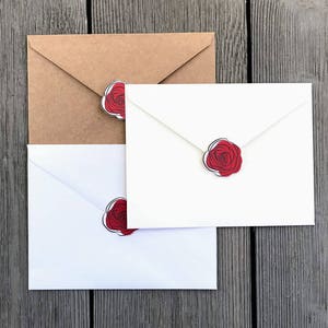May include: Three envelopes with red rose stickers. The envelopes are white and brown.