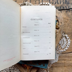 May include: A book titled "Essays: First Series" by Ralph Waldo Emerson. The book's contents page lists the essays and their corresponding page numbers. The essays include "History", "Self-Reliance", "Compensation", "Spiritual Laws", "Love", and "Friendship".