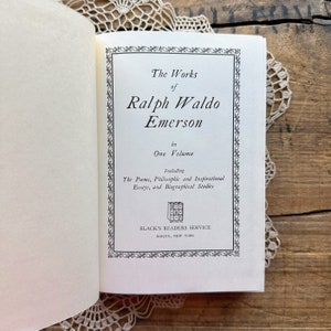 May include: A book cover with a black and white design. The title is "The Works of Ralph Waldo Emerson" in one volume. It includes poems, philosophical and inspirational essays, and biographical studies. The book is published by Black's Readers Service in Roslyn, New York.