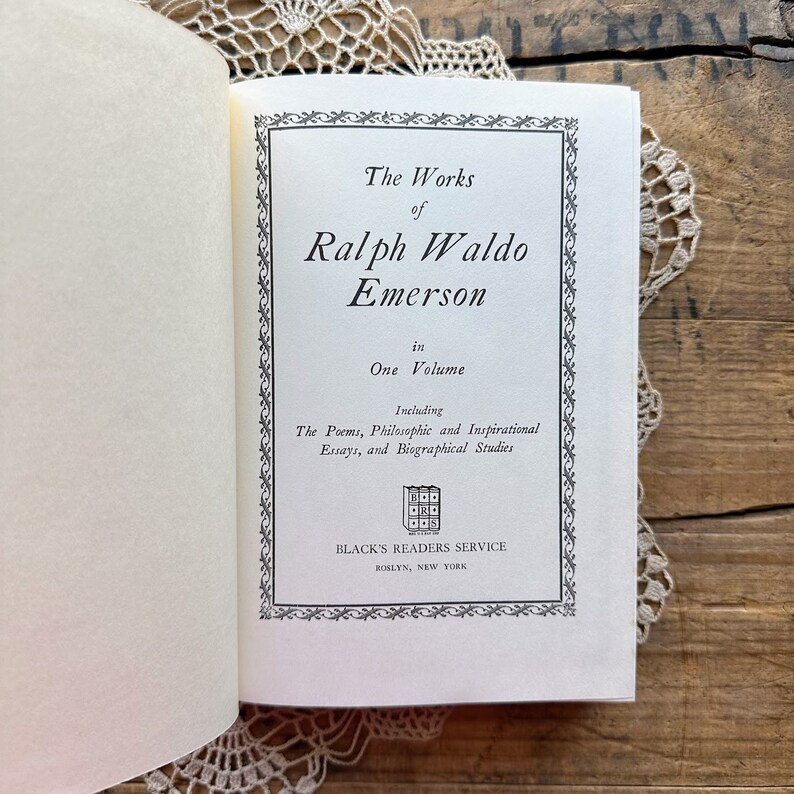 May include: A book cover with a black and white design. The title is "The Works of Ralph Waldo Emerson" in one volume. It includes poems, philosophical and inspirational essays, and biographical studies. The book is published by Black's Readers Service in Roslyn, New York.